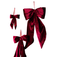 Three red velvet bows of varying sizes on a dark wooden background