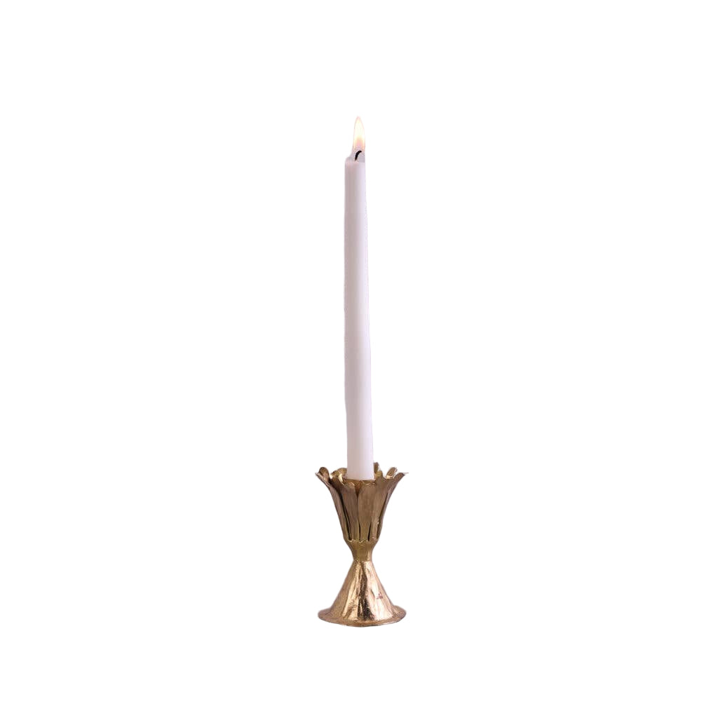 Gold candle holder with a lit white candle on a gray surface and light gray background