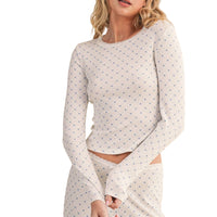 Woman wearing a polka dot long-sleeve top and pants on a beige background