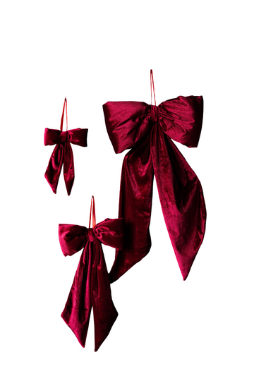 Three red velvet bows of varying sizes on a dark wooden background